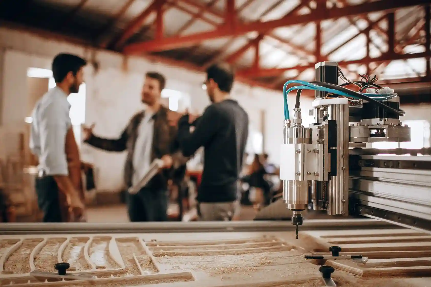 Manufacturing engineers discussing a project inside an industrial workshop with CNC equipment